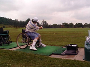 A man seated in a wheelchair swings his golf club.