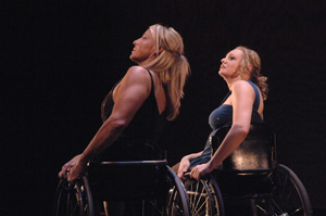 Two women who use wheelchairs are dancing in a modern dance performance.
