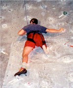 Man with a lower extremity amputation is rock climbing indoors.