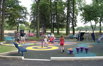 Four spinning pieces of equipment are dispersed on this playground. The 4- to 6-foot use zone around each piece of equipment is colorfully designed with stripped and swirling circles on the unitary rubber ground surface.