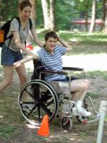 Photo of a young man using a wheelchair being pushed through and obstacle course.